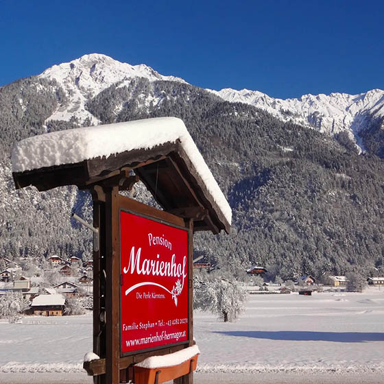 Sign for the Pension Marienhof covered in snow in Nassfeld, Austria