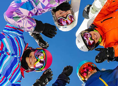 Happy students on a ski trip with bright blue sky backdrop