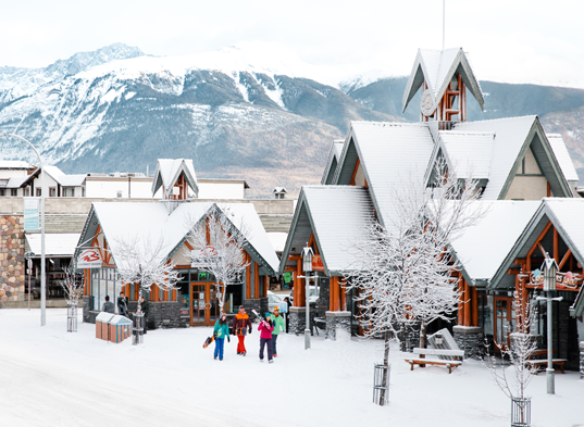 A snow scene in Jasper ski resort of snowy rooftops and mountain scenery.