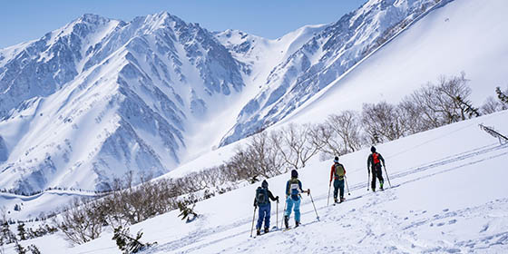 School group posing at Tsugaike with snow-covered mountains in the background