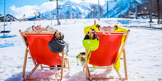 Two skiers chilling on deckchairs in the snow