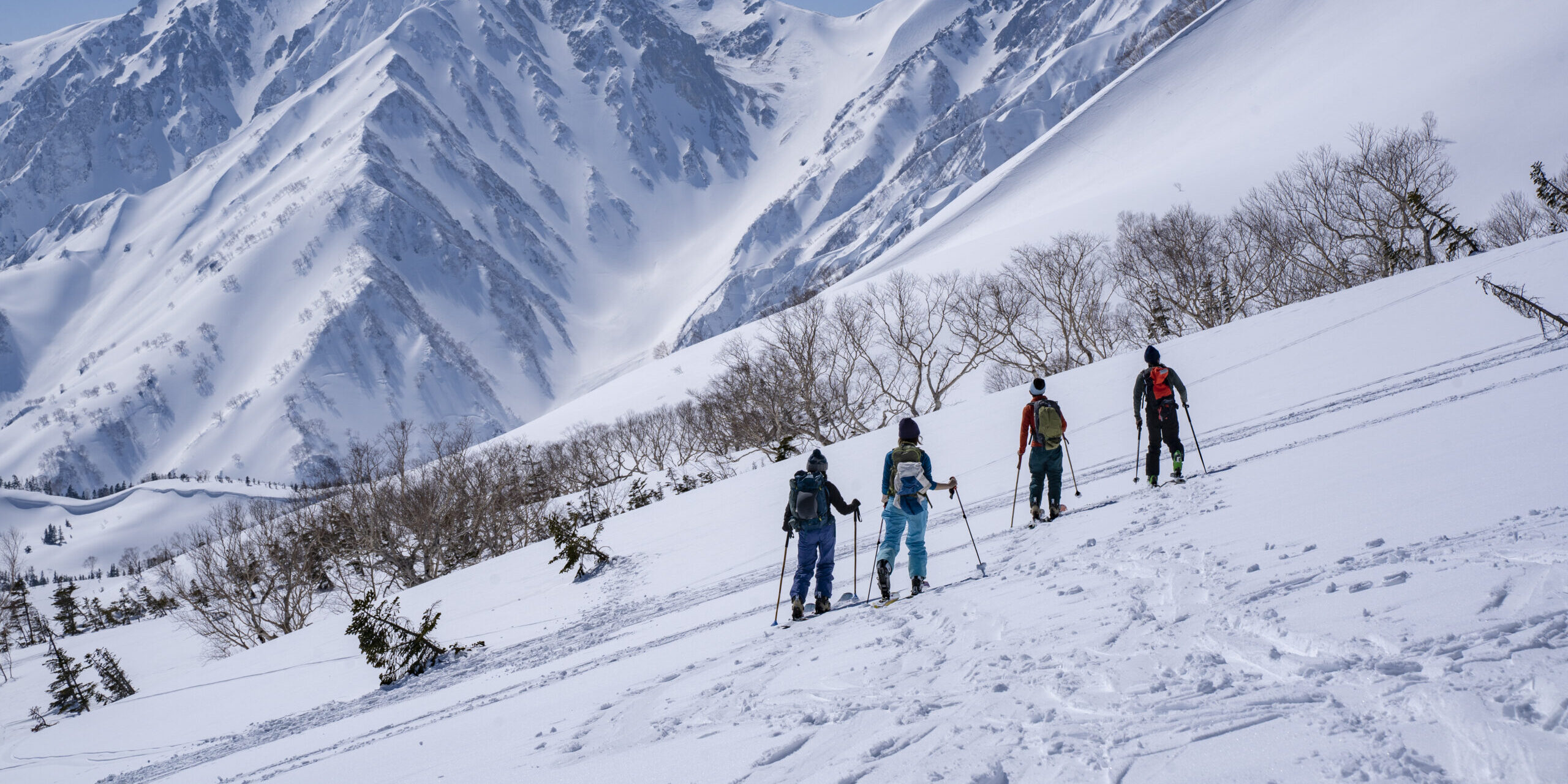 School group posing at Tsugaike with snow-covered mountains in the background