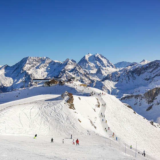 Skiers and snowboarders on the top station slope in Courchevel winter resort, France.