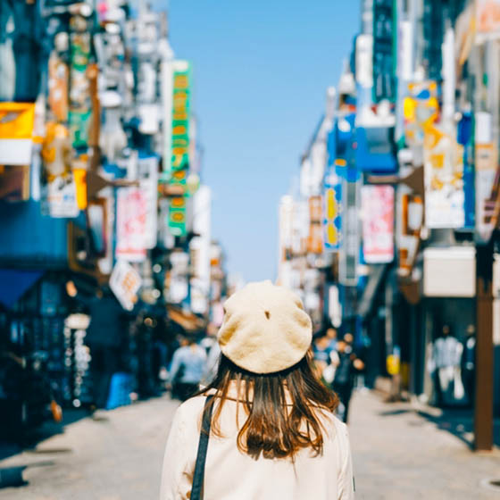 Female student standing in a street lined with colourful Japanese signs in Tokyo