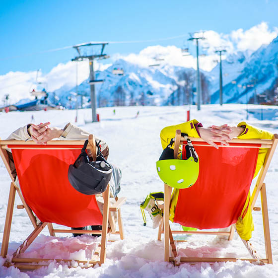 Two skiers chilling on deckchairs in the snow