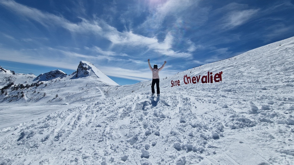 Skier posing next to a Serre Chevalier sign in the snow