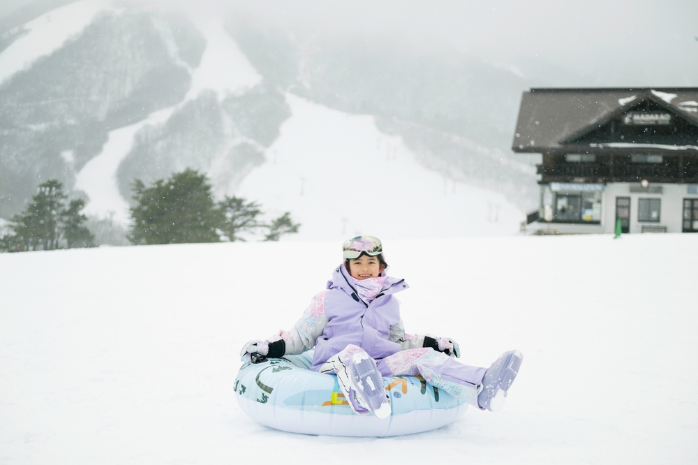 Young girl on an inflatable sledge playing in the snow in Japan